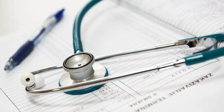 A stethoscope and pen resting on a medical report in a healthcare setting.