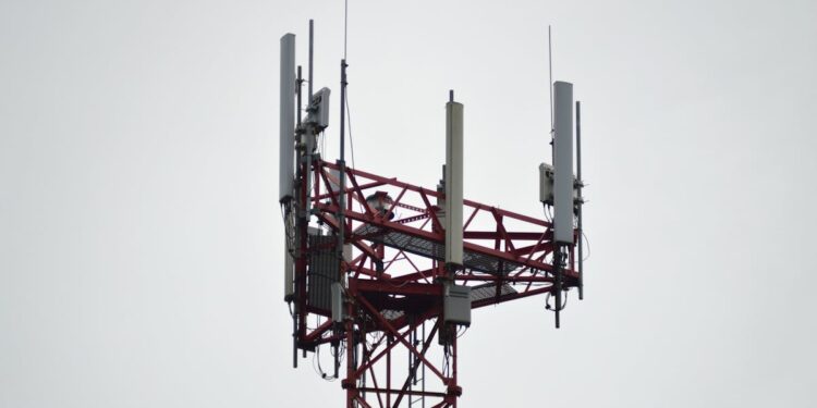 A red communication tower with antennas stands tall against a gray sky.