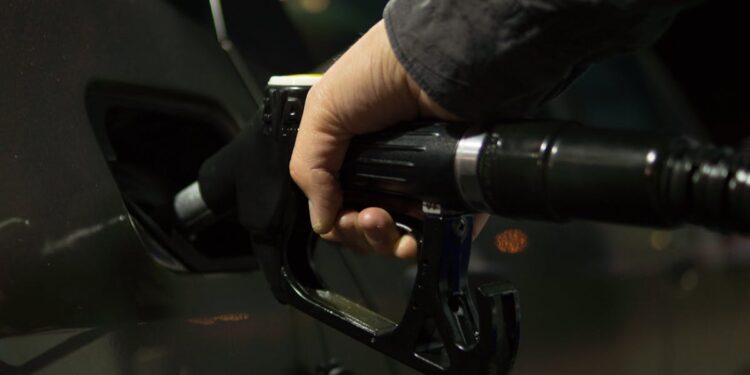 Close-up of a person refueling a car at a gas pump during night.